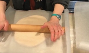 Rolling out the dough between 2 layers of parchment.
